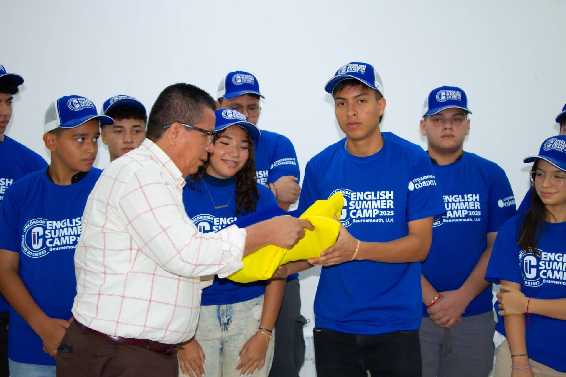 El rector Jairo Torres Oviedo entregó simbólicamente las banderas de Colombia y de la Universidad de Córdoba a los estudiantes que participarán en el campamento de verano en Reino Unido, acompañados por sus padres y directivos del Centro de Idiomas.